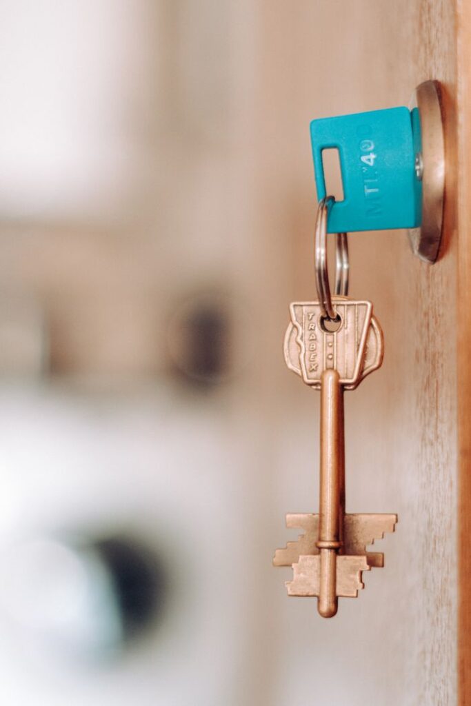 A brass key with a blue plastic tag in a door lock indoors.