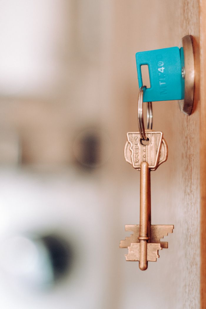 A brass key with a blue plastic tag in a door lock indoors.