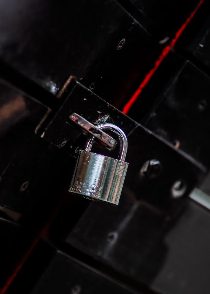 about-02 Close-up view of a metal padlock securing a dark door latch, symbolizing safety and protection.